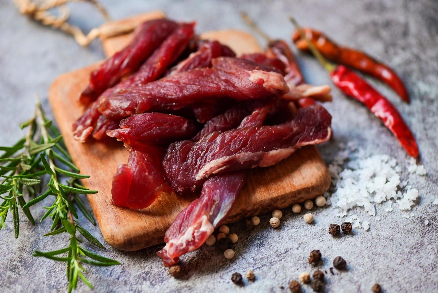 carne seca com ervas e especiarias - carne seca na placa de madeira, carne seca crua para cozinhar, carne seca na comida tailandesa foto