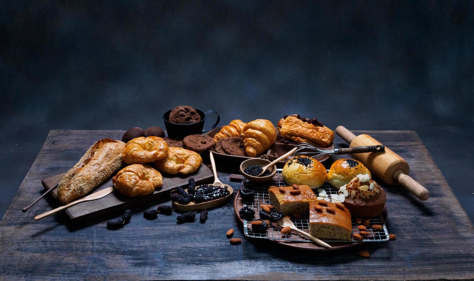 vista superior pão fresco passas marrom gergelim padaria feita de farinha de trigo comida caseira adequada para uma alimentação saudável no chão de mesa de madeira preto rústico fundo escuro foto