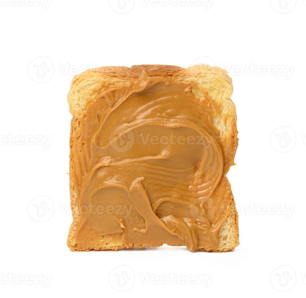 fatia quadrada de pão de trigo untada com manteiga de amendoim isolada no fundo branco foto