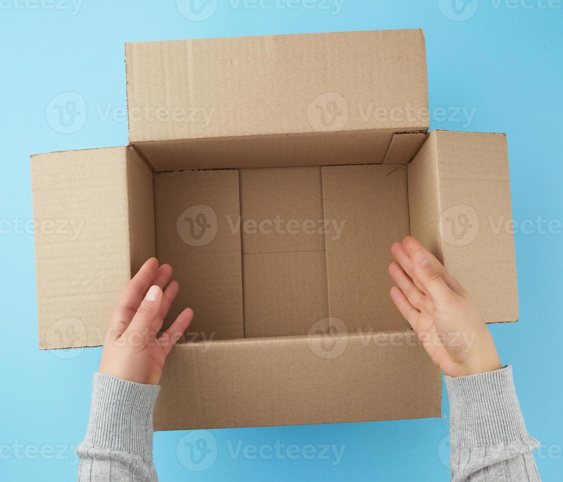 mãos femininas estão segurando uma caixa aberta vazia de papelão marrom foto