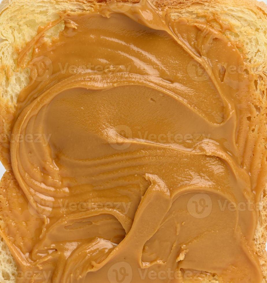 textura de manteiga de amendoim espalhada no pão, full frame foto