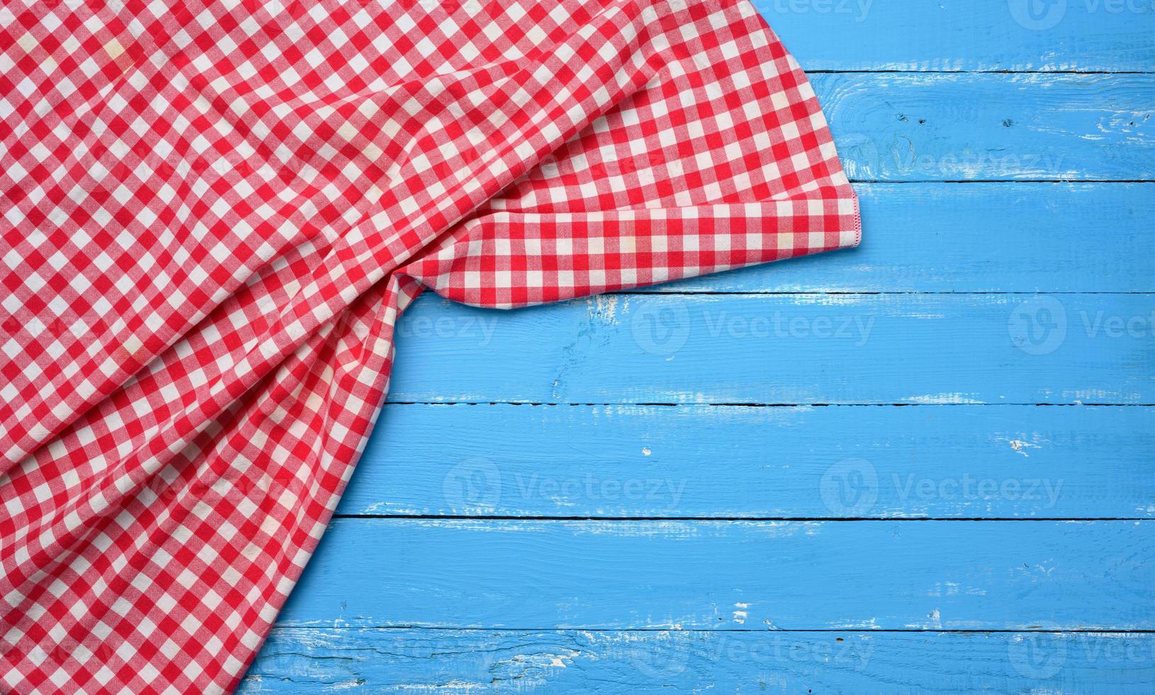 guardanapo de cozinha de algodão vermelho e branco dobrado sobre um fundo azul de madeira foto