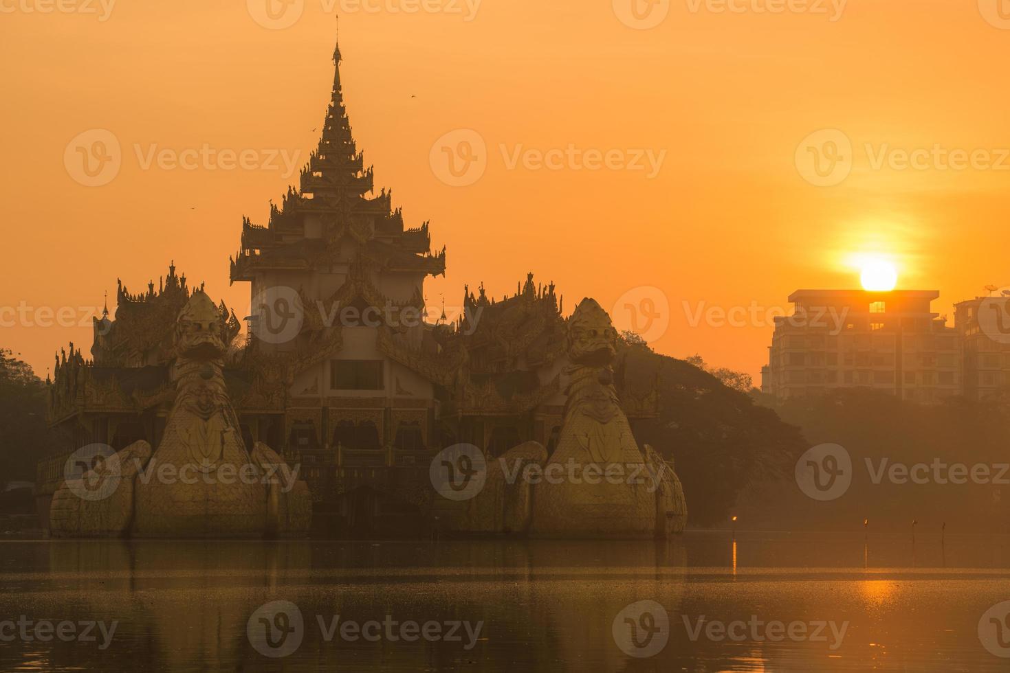 belo nascer do sol sobre o palácio karaweik no distrito de yangon, em myanmar. foto