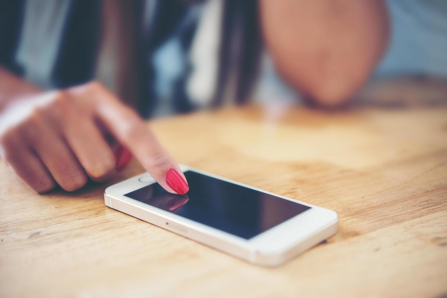 close-up das mãos de uma mulher tocando o celular com a tela do espaço de cópia em branco foto