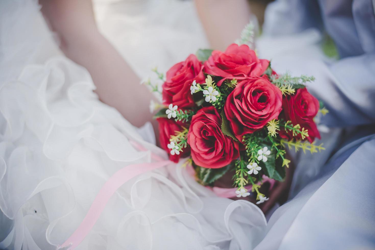 noiva segura nas mãos um buquê de rosa vermelha foto