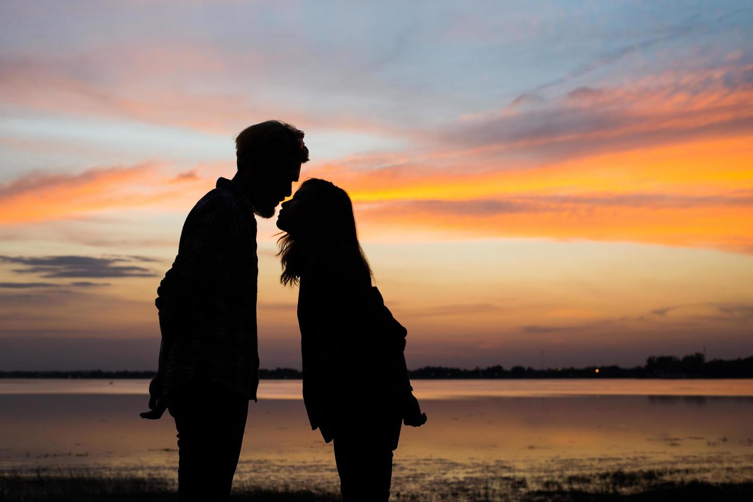 silhueta de um jovem casal junto durante o pôr do sol foto