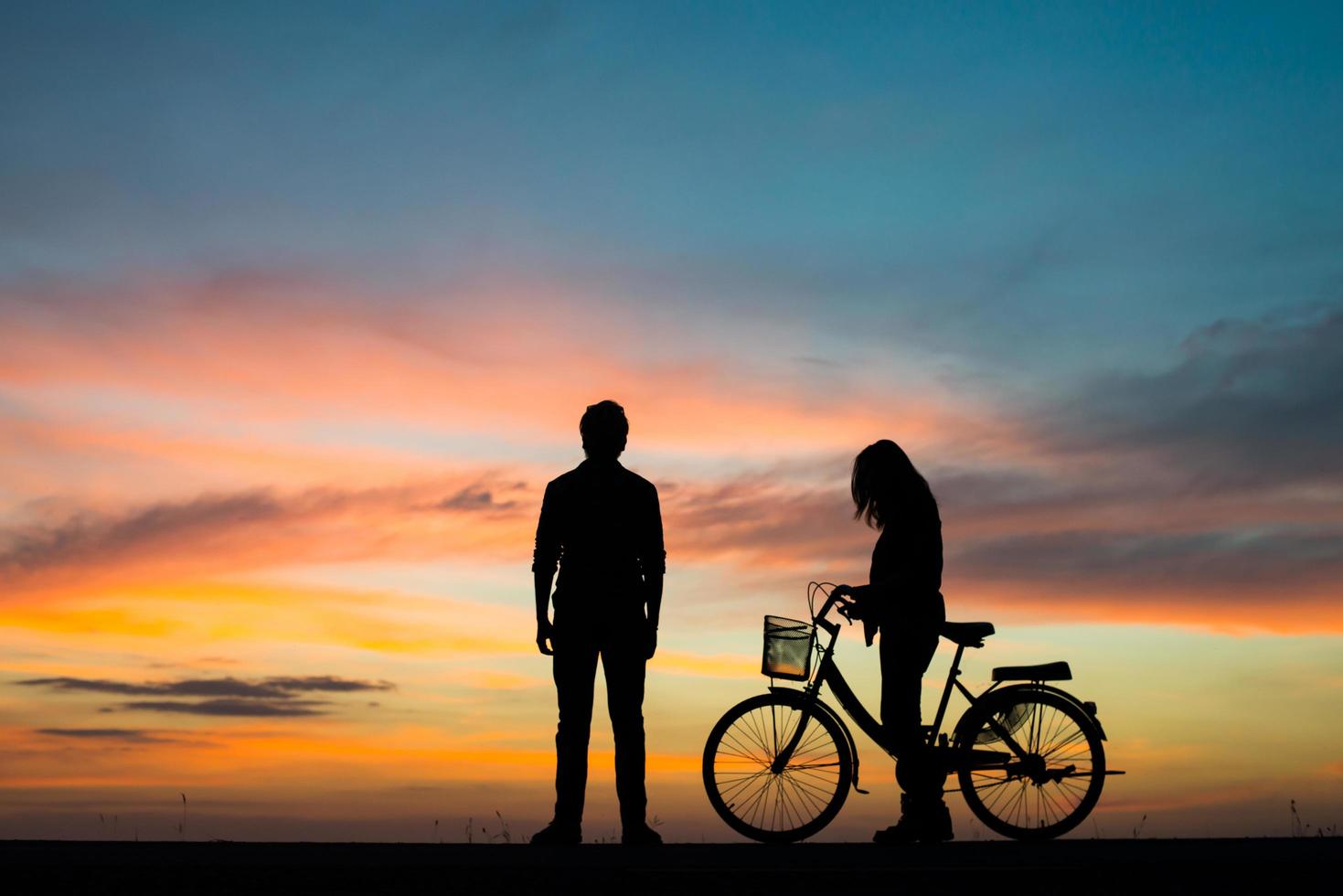 silhueta de um jovem casal junto durante o pôr do sol foto