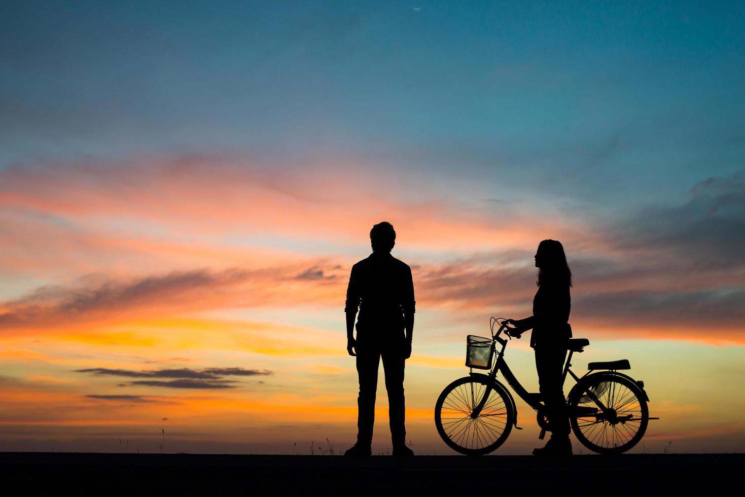 silhueta de um jovem casal junto durante o pôr do sol foto