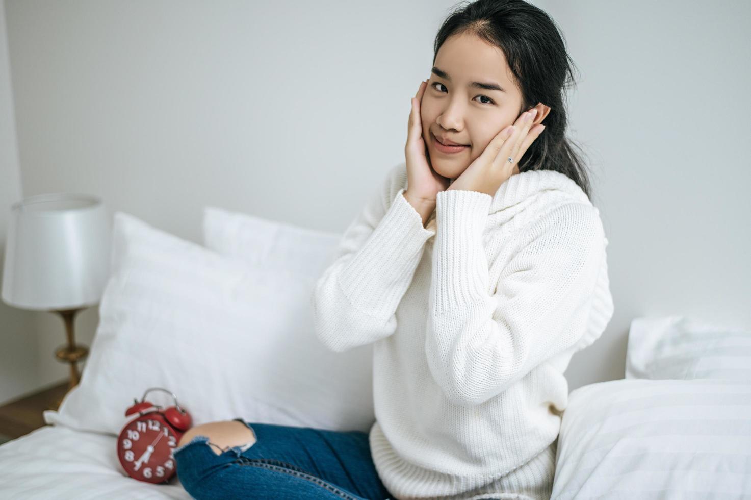 jovem sentada na cama sorrindo alegremente foto