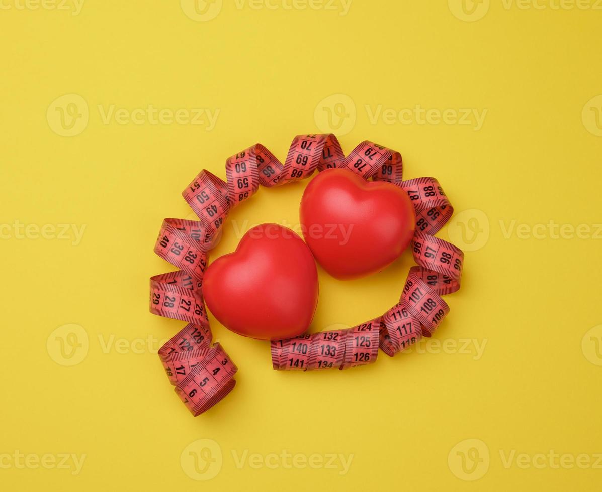 coração vermelho e fita métrica vermelha em fundo amarelo foto