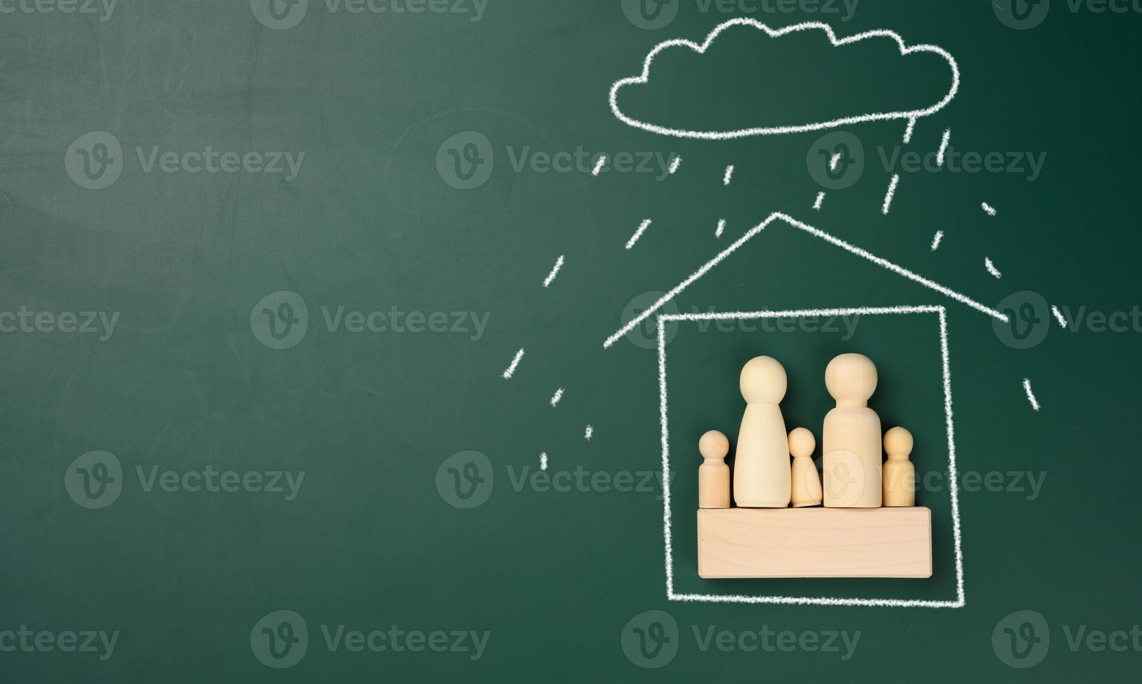 estatuetas de madeira de uma família em uma casa desenhada com giz branco e chuva de uma nuvem. conceito de seguro imobiliário e familiar. proteção contra desastres naturais foto