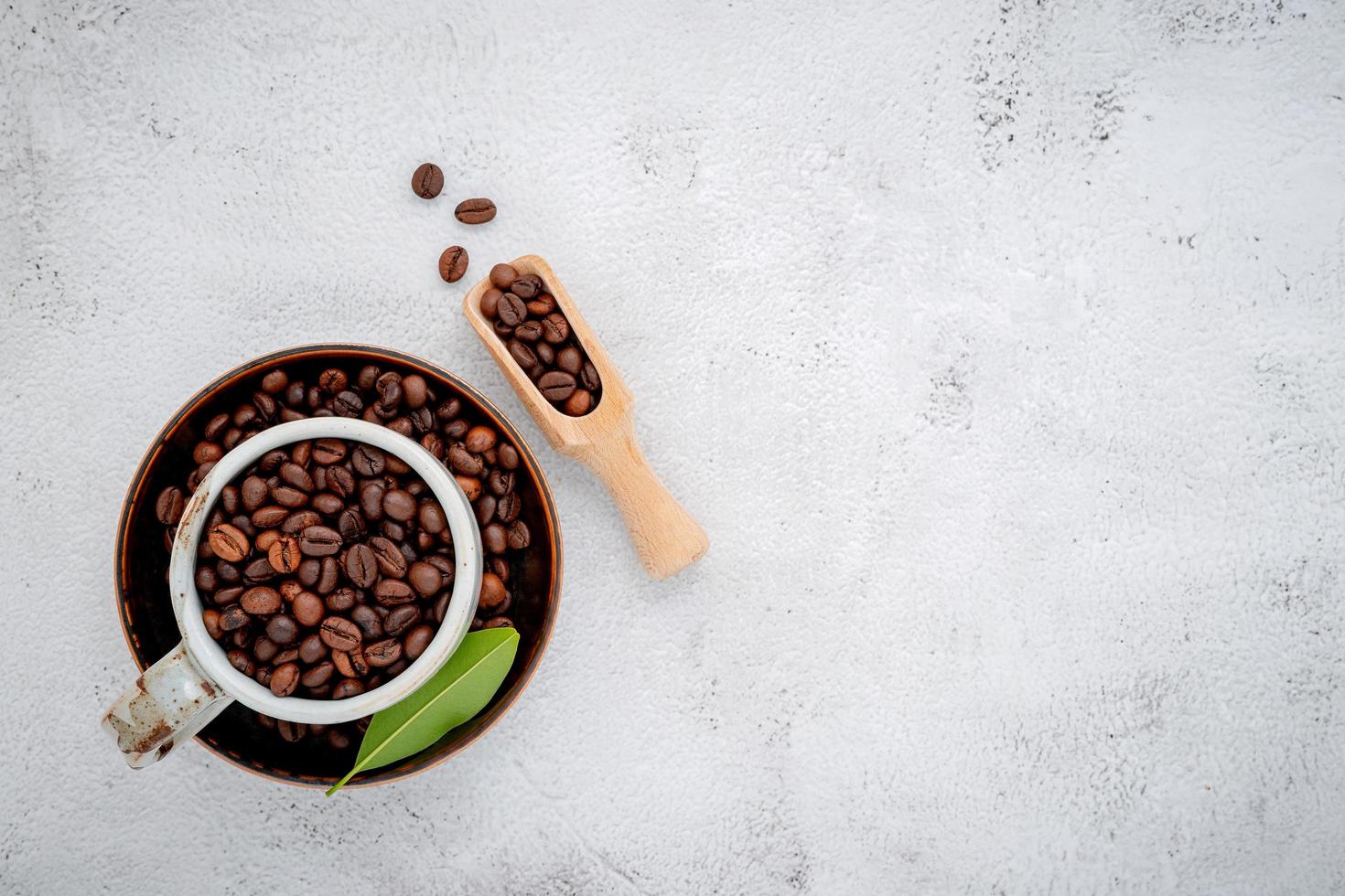 grãos de café torrados com colheres configuradas em fundo branco de concreto foto