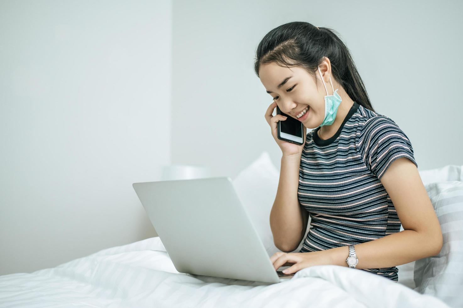 mulher brincando em seu laptop e falando ao telefone foto