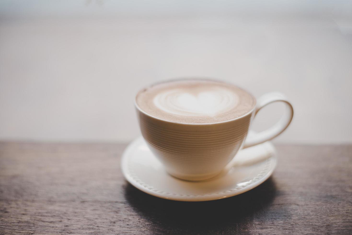 café latte art vintage com formato de coração na mesa de madeira foto