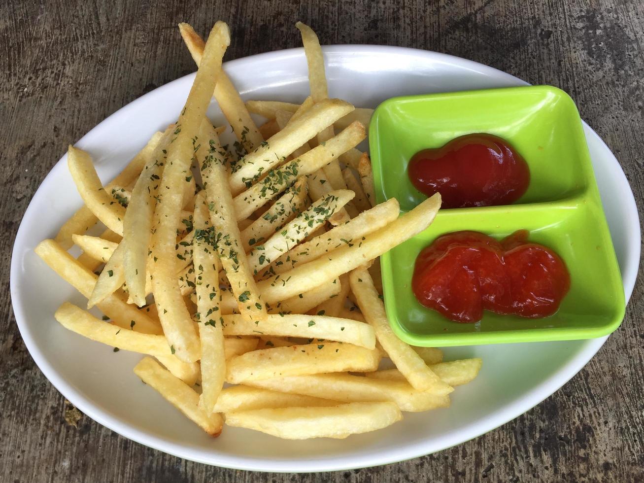 um prato de batatas fritas completo com molho de tomate e molho picante foto