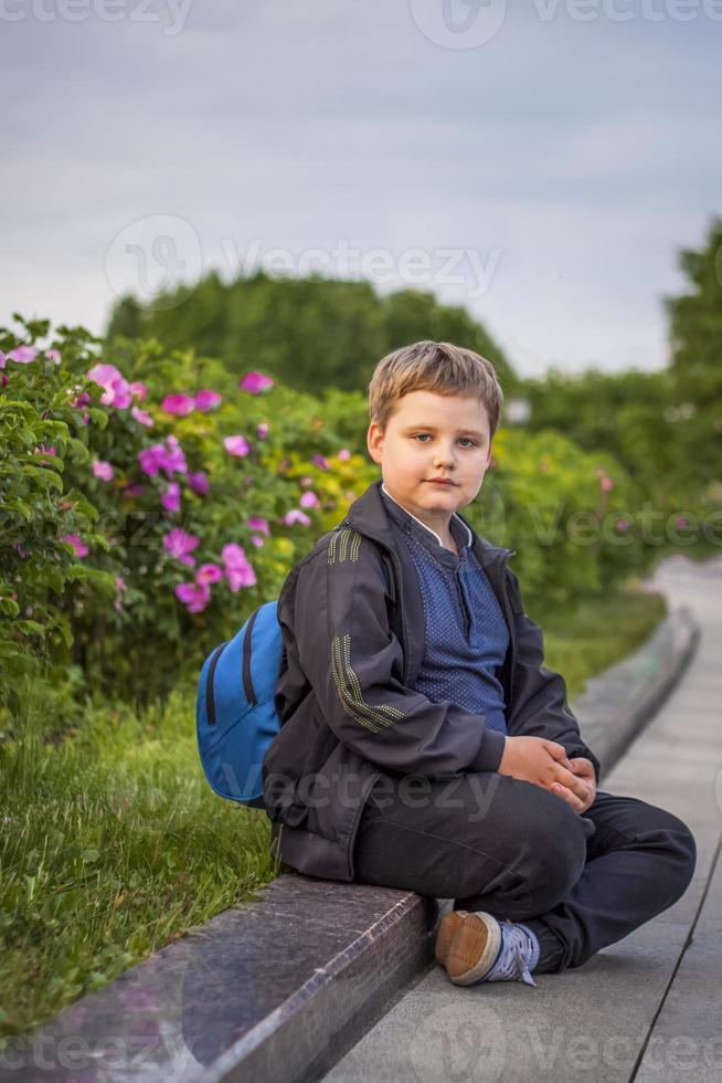 retrato do uma criança, uma Garoto contra a fundo do plantas dentro a ar livre parque. crianças, viagem. estilo de vida dentro a cidade. Centro, ruas. foto