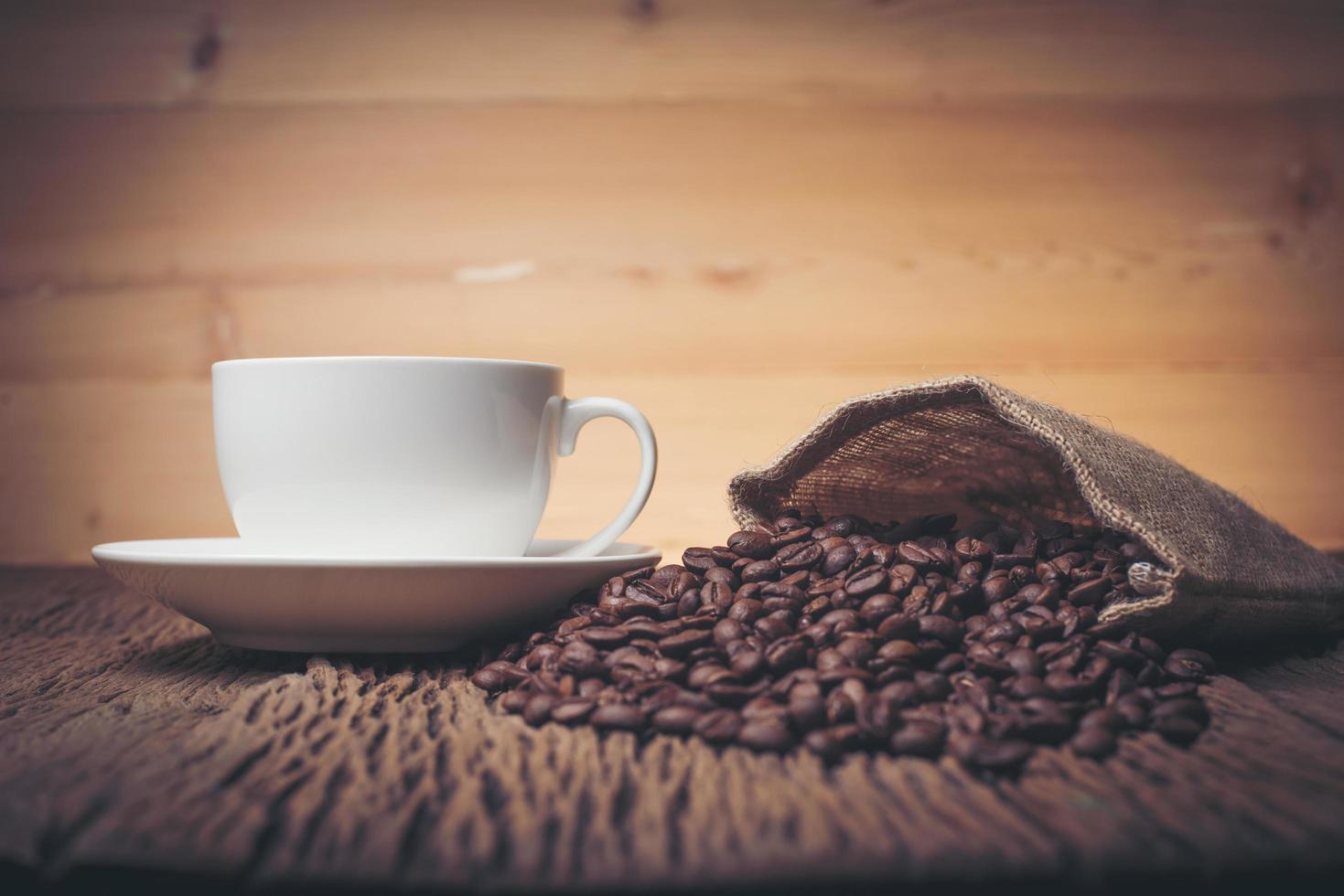 xícara de café com grãos de café em uma mesa de madeira foto