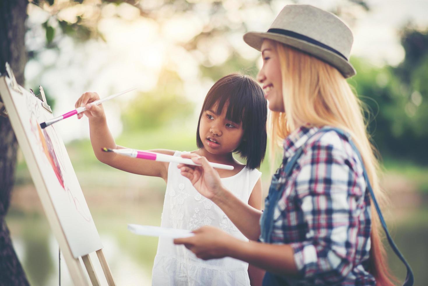 mãe e filhas fazendo desenhos juntas em um parque foto