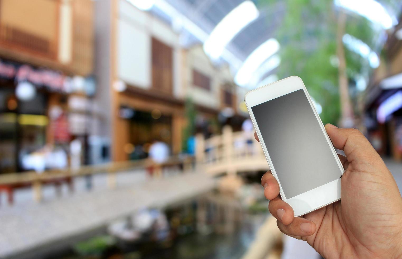 mão segurando telefone no shopping foto