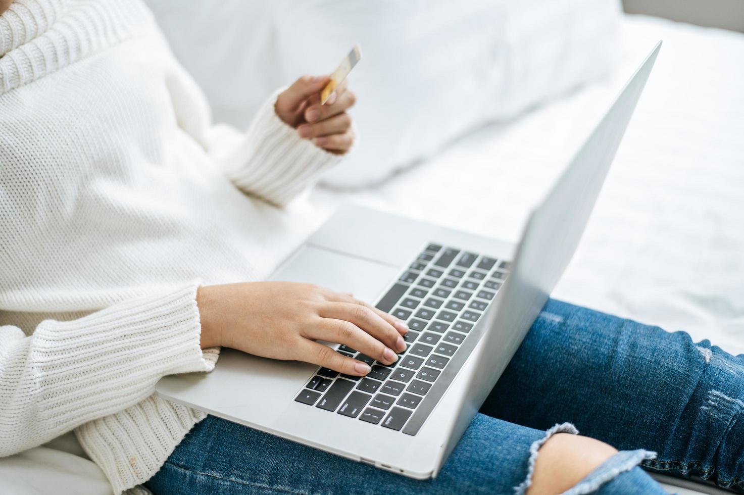 jovem fazendo compras no laptop e segurando um cartão de crédito foto