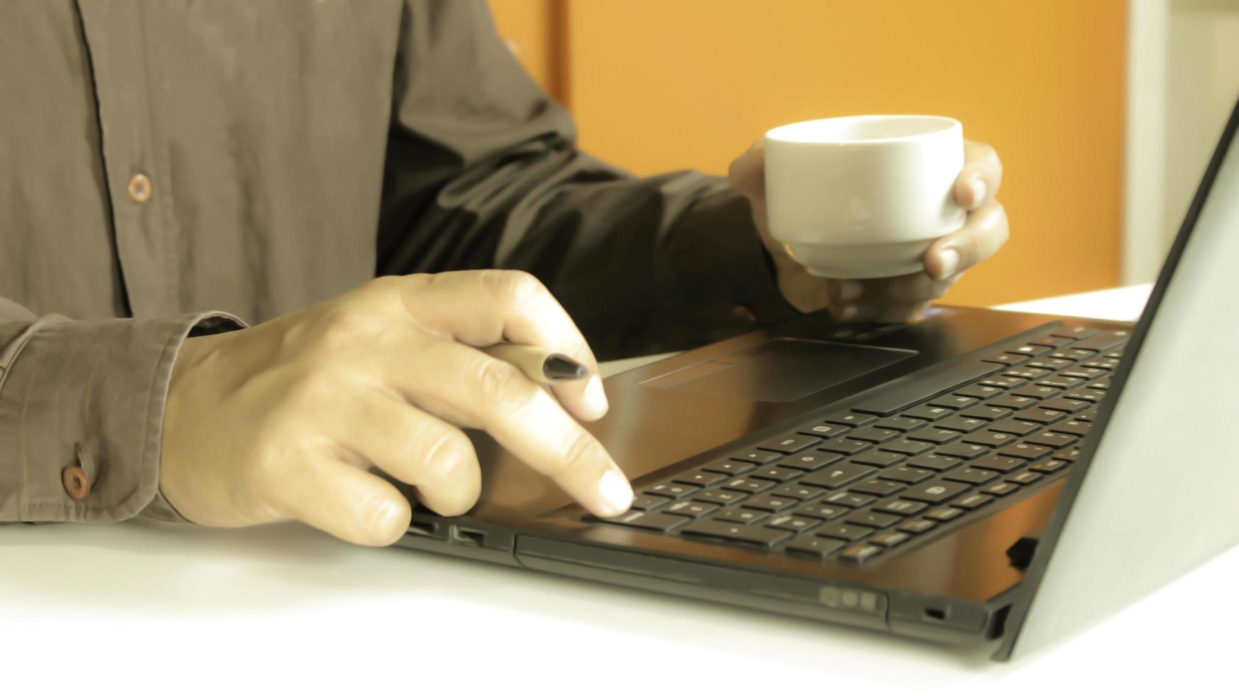 profissional trabalhando em um laptop e tomando café foto