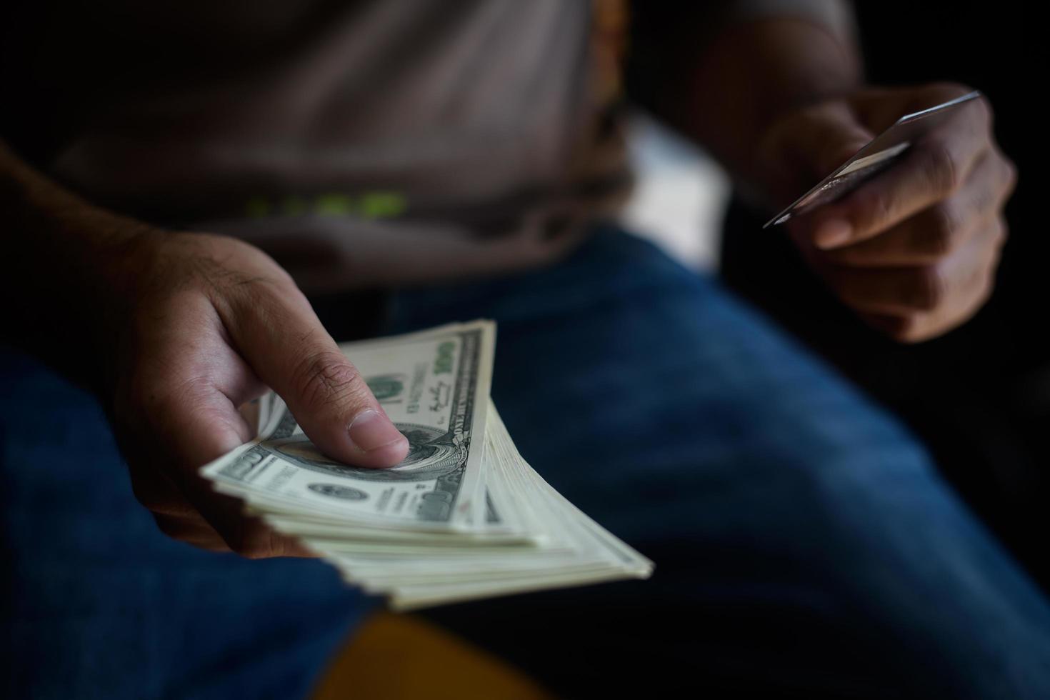 mãos segurando dinheiro com cartão de crédito para compras online foto