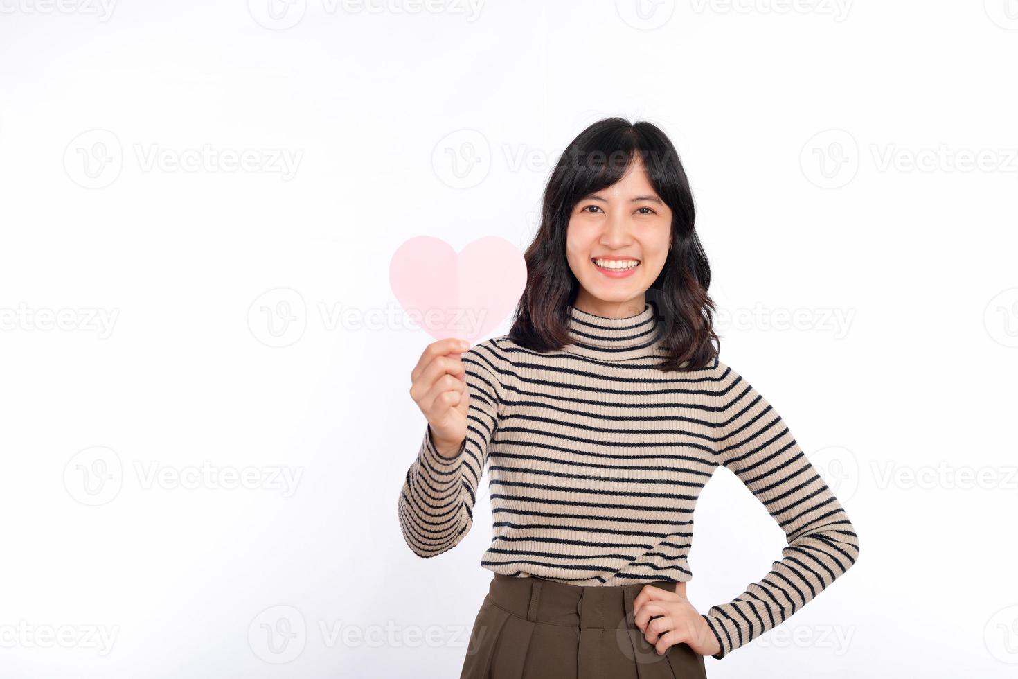 bela jovem asiática segurando um coração de papel em pé contra um fundo branco. bela jovem mulher asiática com coração de papel. foto