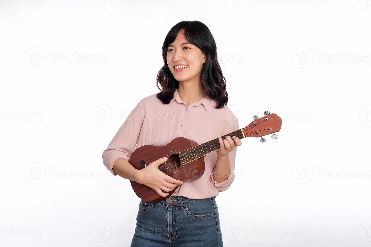 feliz jovem ásia mulher com casual roupas jogando ukulele isolado em branco fundo foto