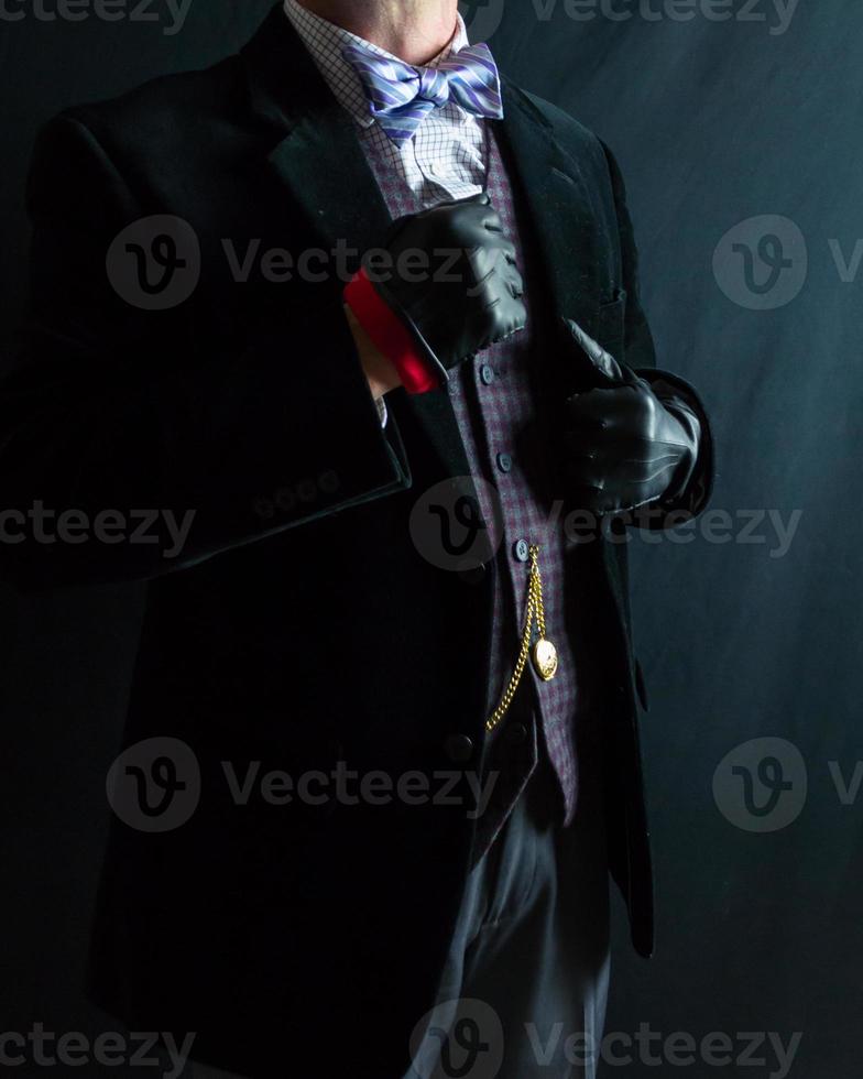 retrato do cavalheiro dentro Sombrio terno e couro luvas em pé generosamente. vintage estilo e retro moda. afiado vestido homem para formal evento. foto