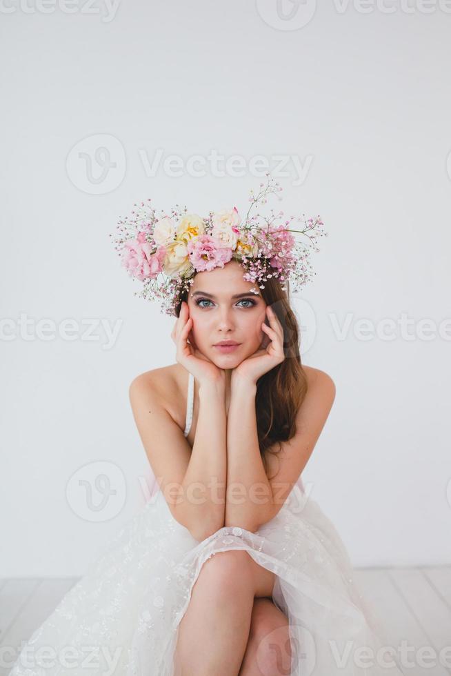 retrato do lindo noiva com flor guirlanda em dela cabeça às branco fundo foto