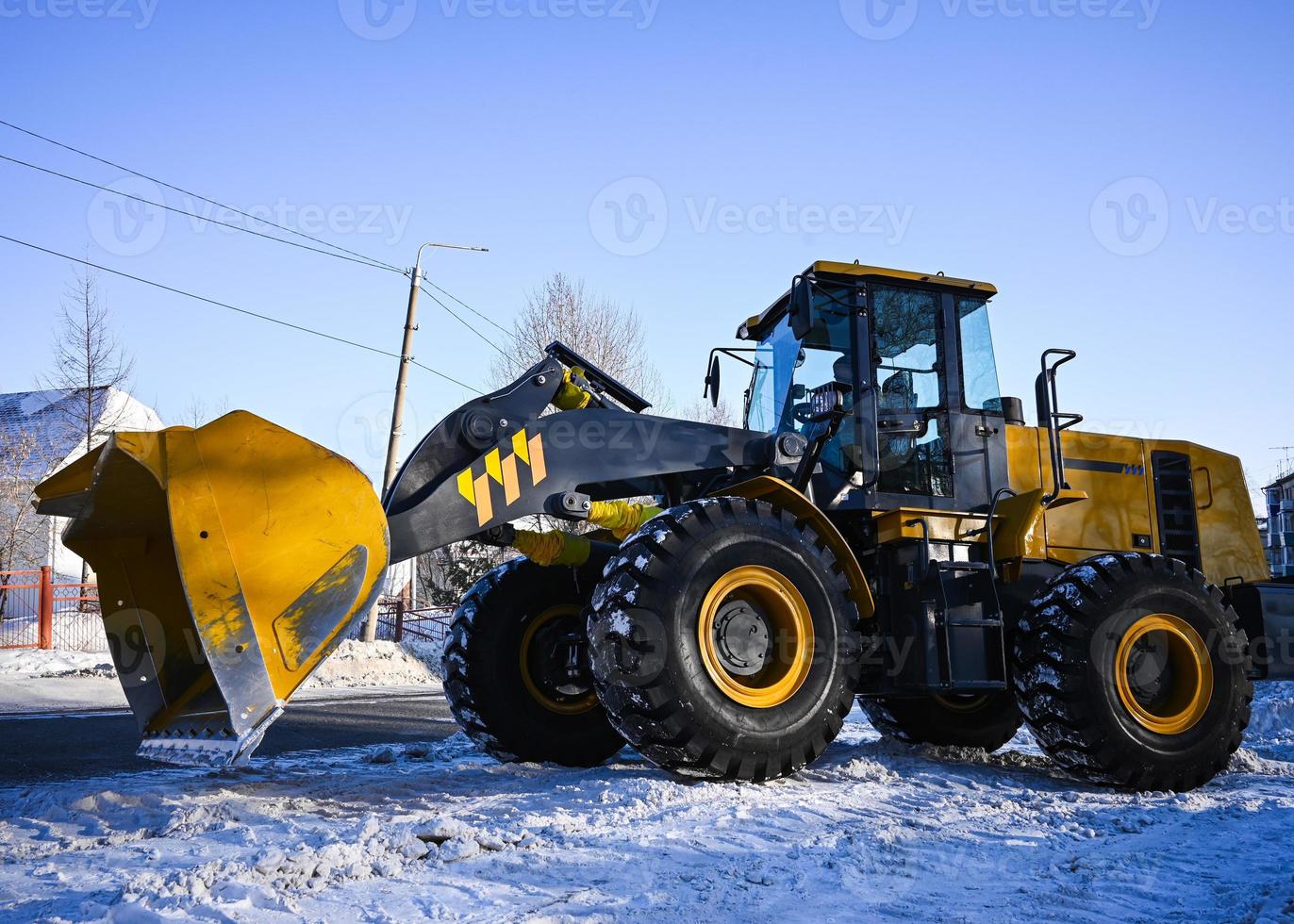 retroescavadeira carregador em a estrada. uma amarelo trator remove neve em a rua. foto