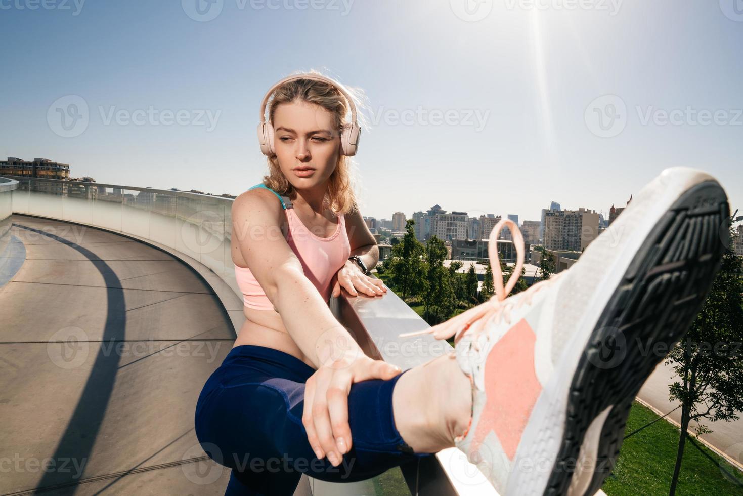 elegante esportivo menina dentro fones de ouvido alongar a músculos do a pernas foto