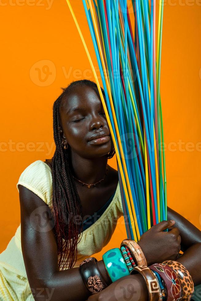 jovem africano menina é jogando com grandes colorida bebendo palhas foto