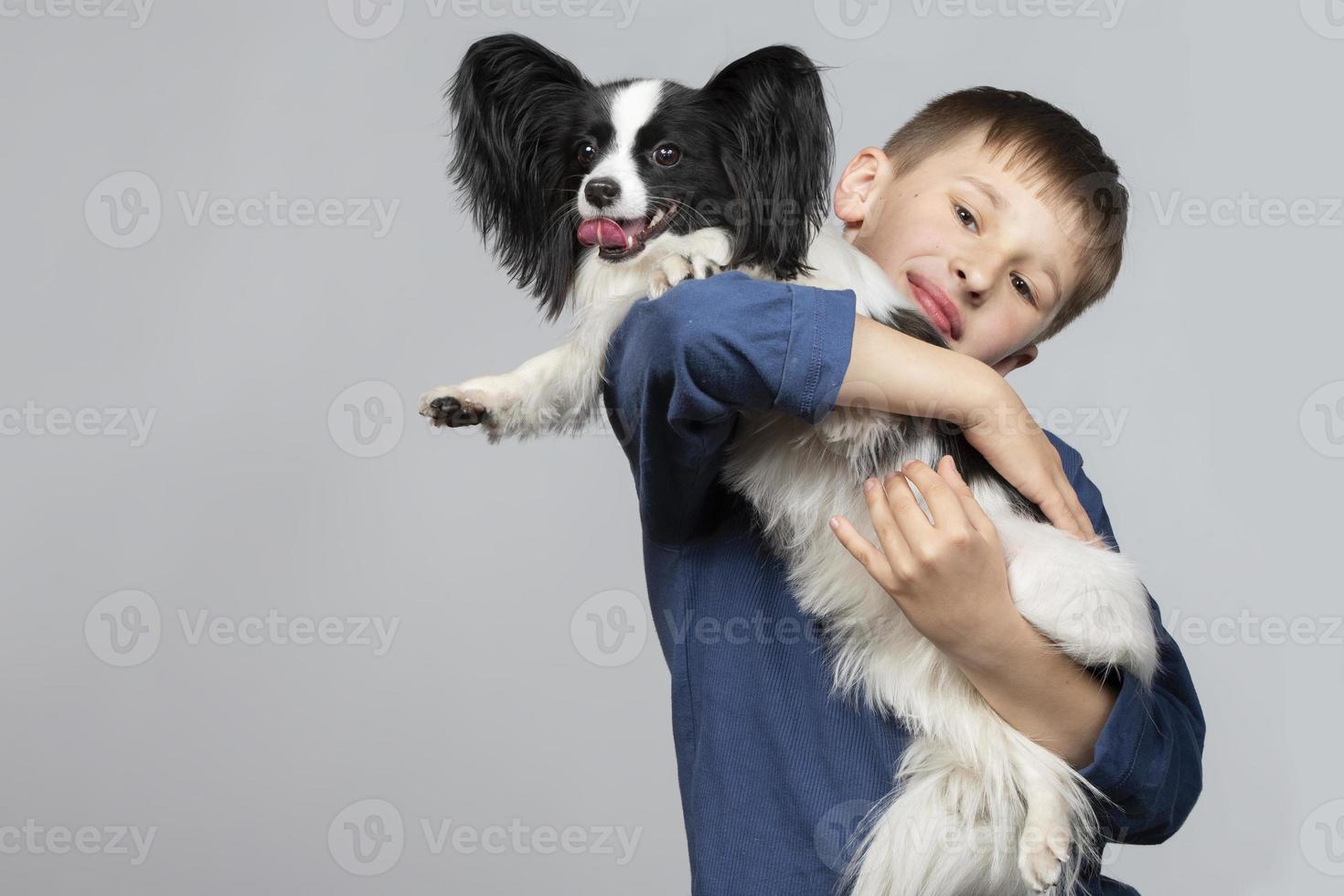 pequeno Garoto com uma engraçado cachorro. a criança é segurando uma papillon filhote de cachorro. animais de estimação com proprietário. foto