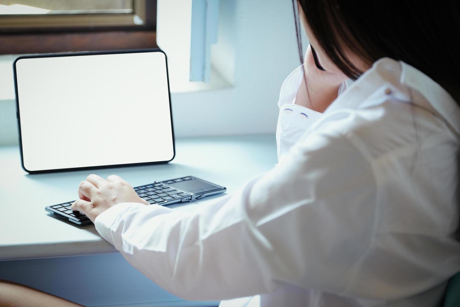 a Novo normal. uma empresária é usando computador e telefone para trabalhos para uma empresa. sobre a Internet em seu escrivaninha às lar. foto