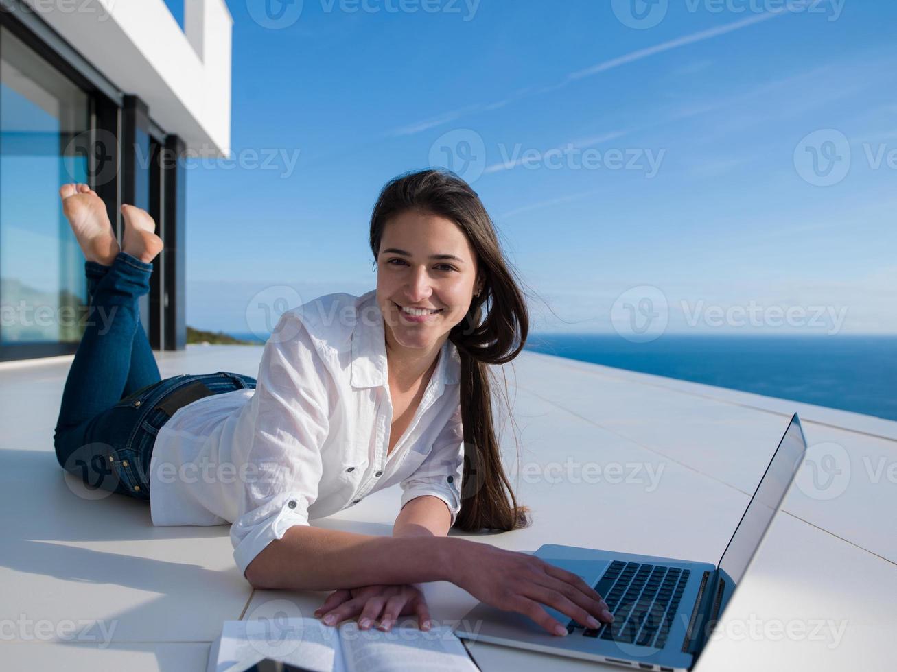 jovem relaxada em casa trabalhando no laptop foto