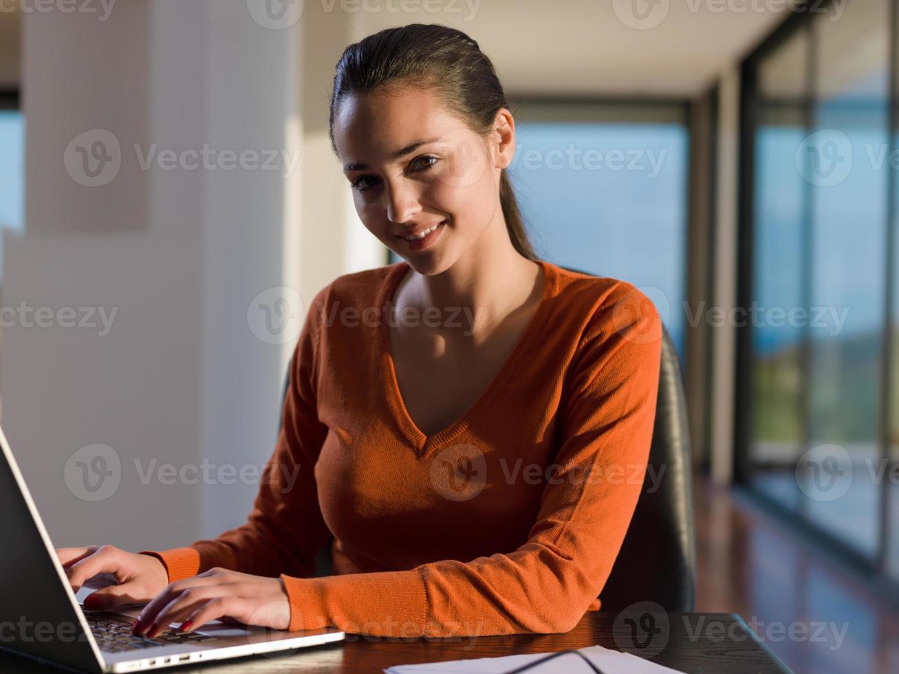 jovem relaxada em casa trabalhando no computador portátil foto