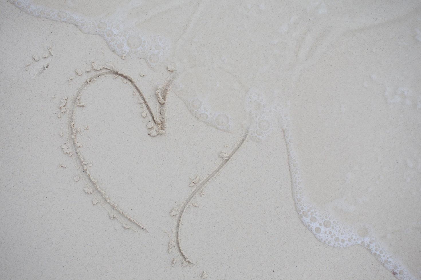 corações desenhados na areia de uma praia foto