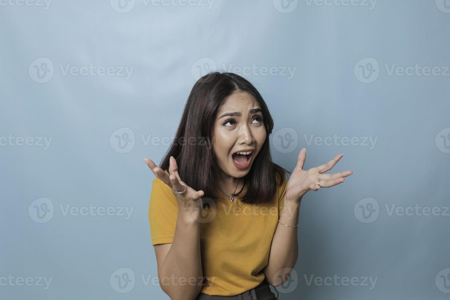 bela jovem chorando sentindo-se muito deprimida isolada por fundo azul gritando alto foto