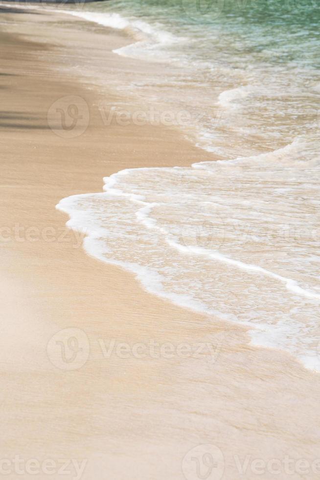 fechar acima ondas textura lapidação através intocado areia costa ensolarado verão. foto