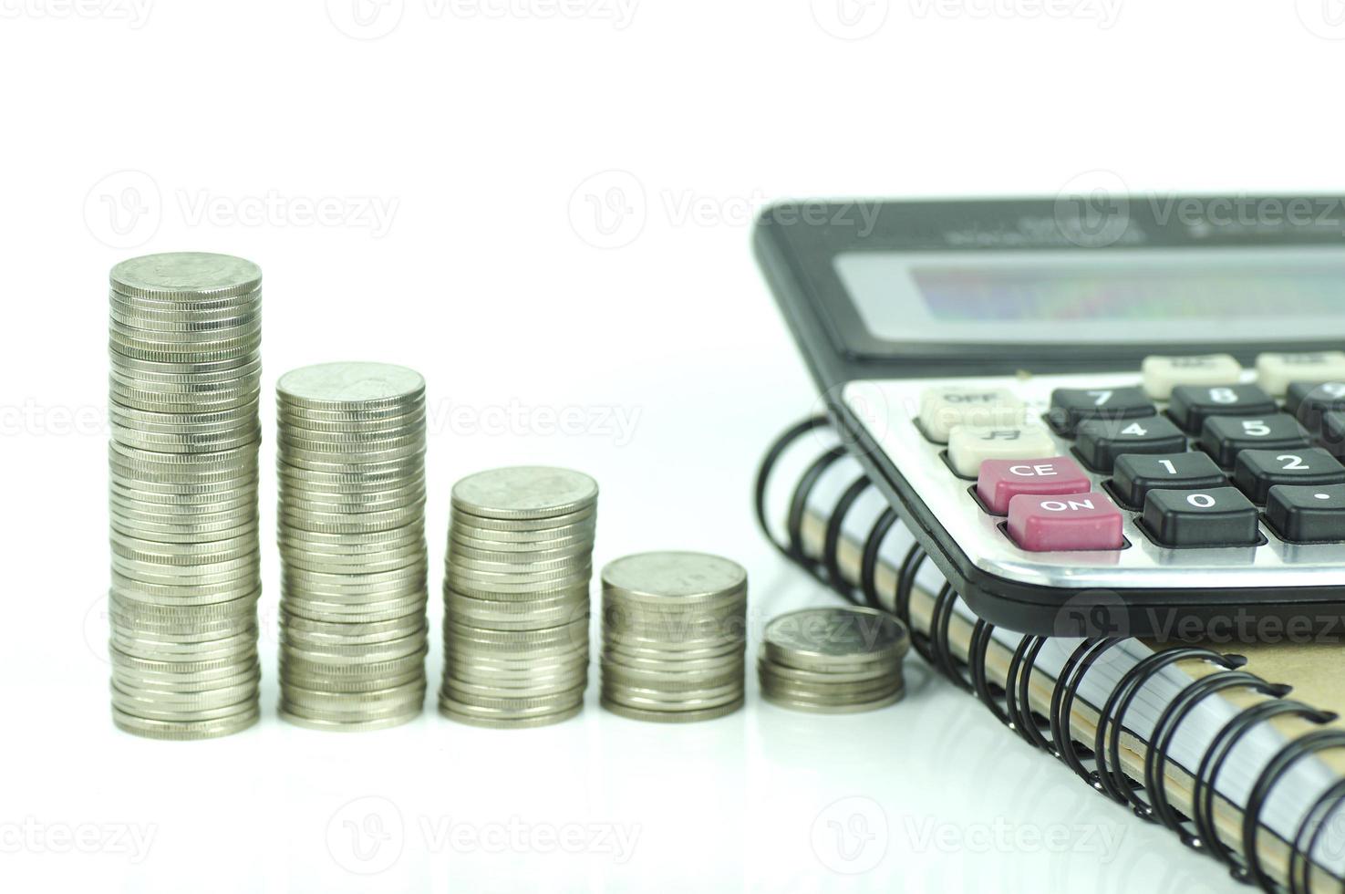moedas e calculadora em fundo branco foto