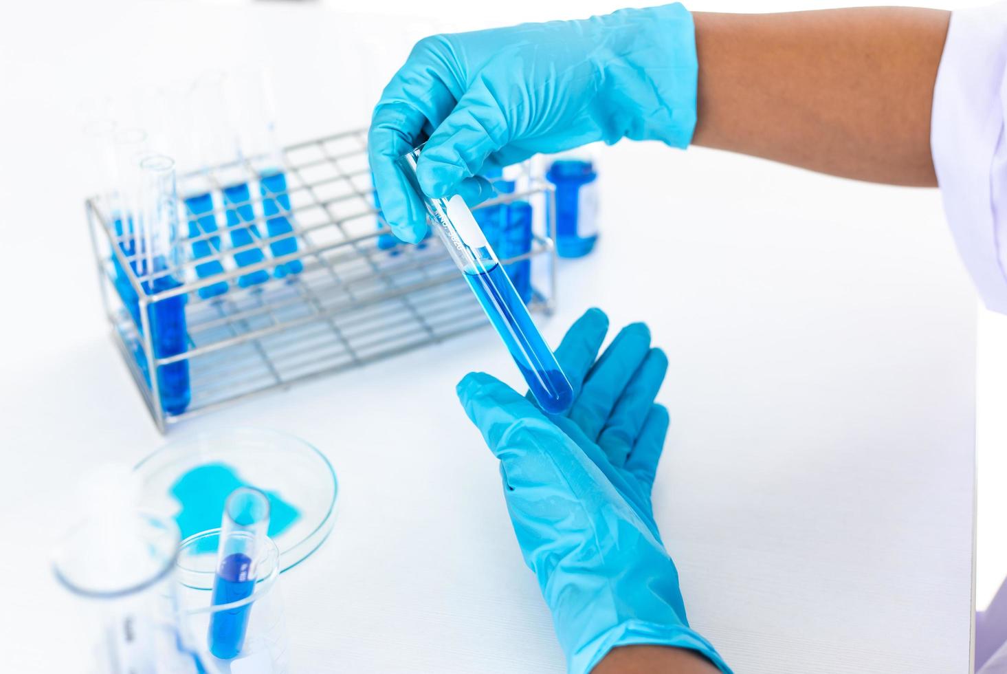 cientista olhando para um líquido azul em um tubo de ensaio foto
