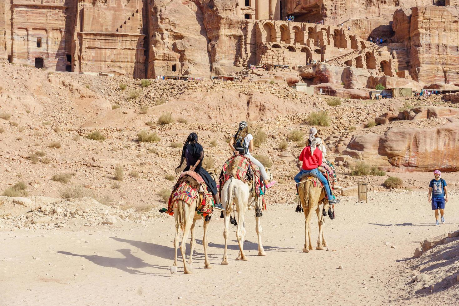 turistas montando camelos em petra, jordânia, 2018 foto