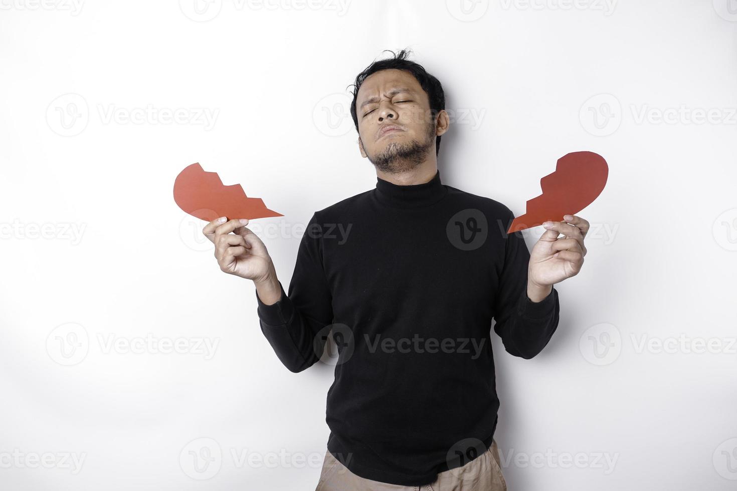 lindo jovem ásia homem expresso dele tristeza enquanto segurando quebrado coração isolado em branco fundo foto