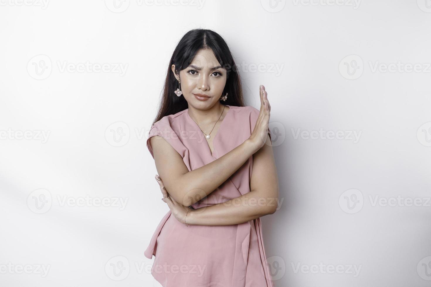 lindo ásia mulher vestindo Rosa blusa com mão gesto pose rejeição ou proibição com cópia de espaço foto