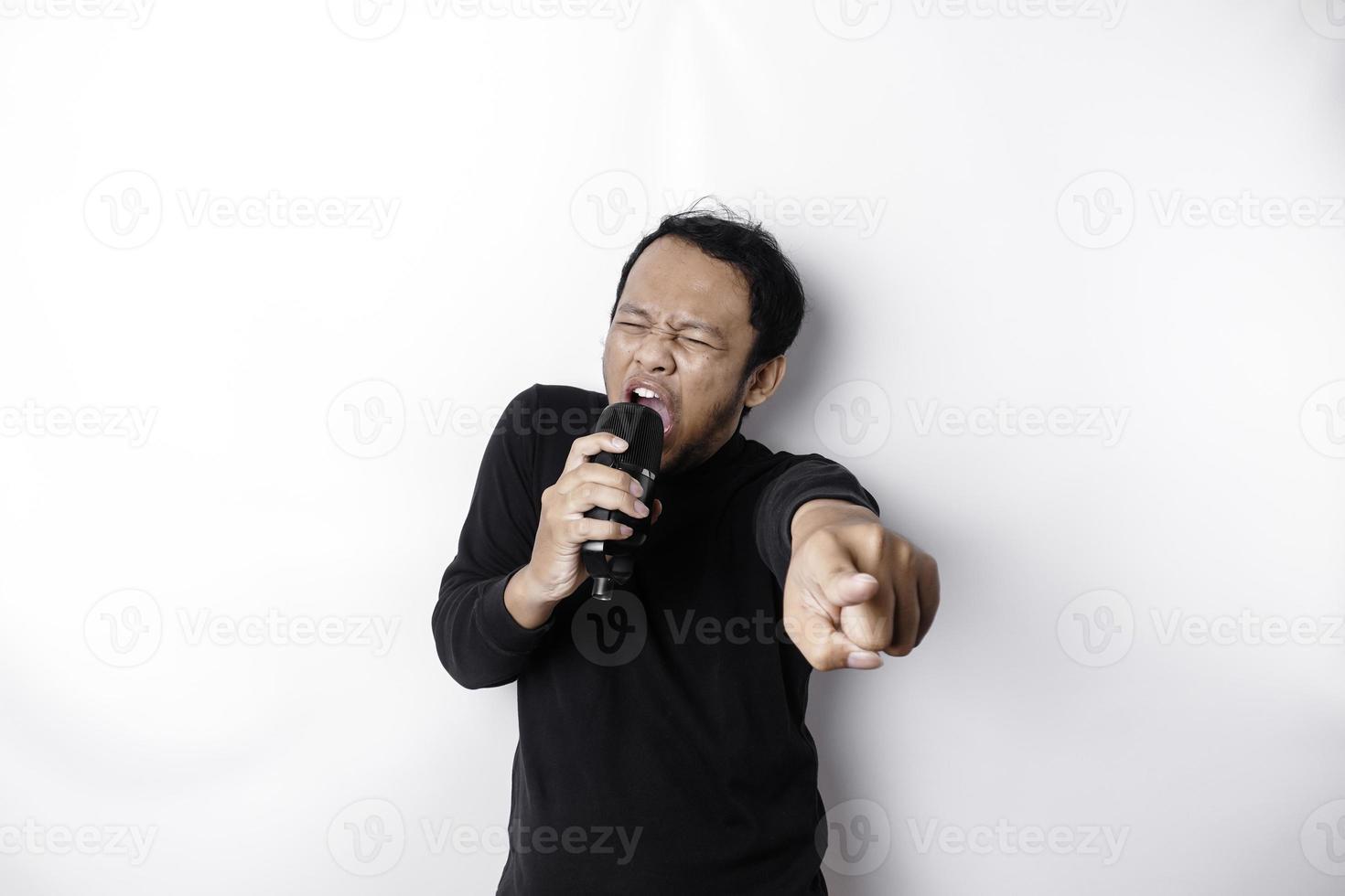 retrato de homem asiático despreocupado, se divertindo karaokê, cantando no microfone em pé sobre fundo branco foto