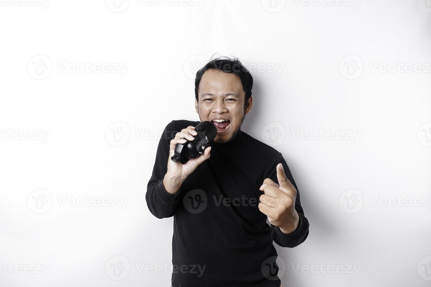 retrato de homem asiático despreocupado, se divertindo karaokê, cantando no microfone em pé sobre fundo branco foto