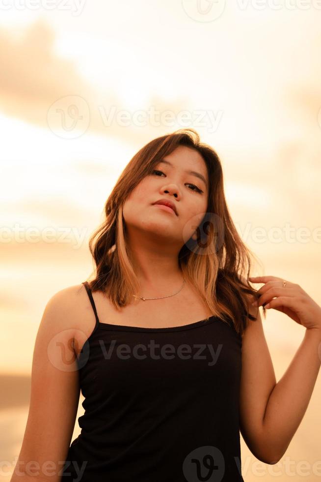 retrato do a indonésio mulher dentro Preto roupas e Loiras cabelo posando muito belas em a de praia foto
