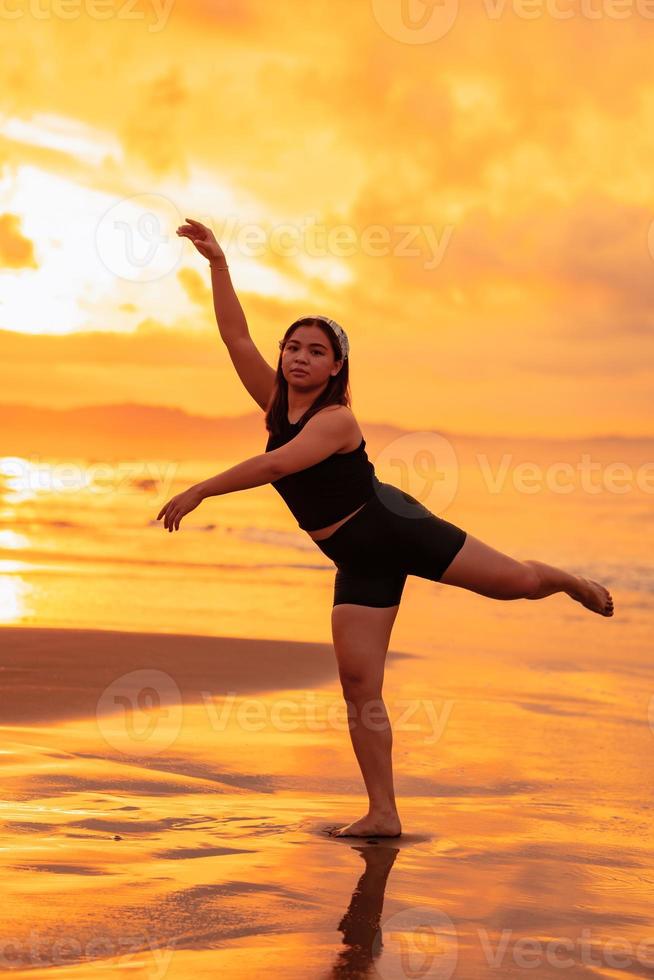 a ásia adolescente dançando balé dentro Preto para uma festival de a de praia foto