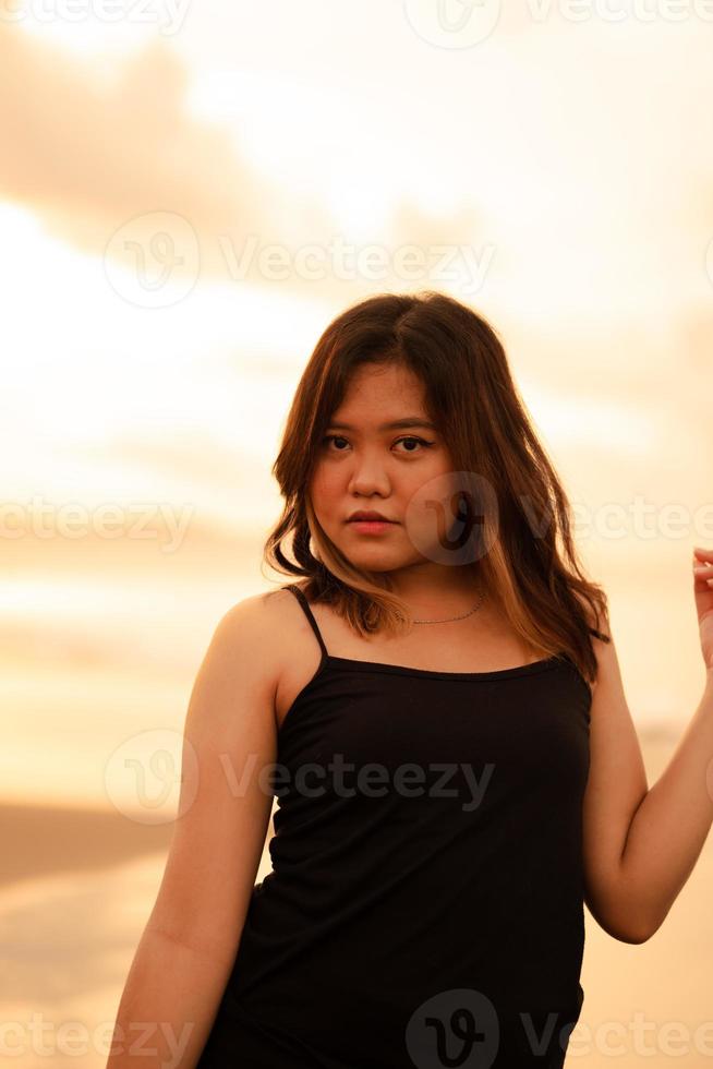 retrato do a indonésio mulher dentro Preto roupas e Loiras cabelo posando muito belas em a de praia foto